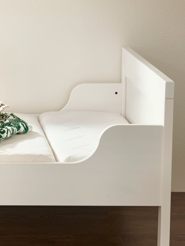 Białe, rosnące łóżko dziecięce SUNDVIK z materacem i leżącą na nim pościelą.