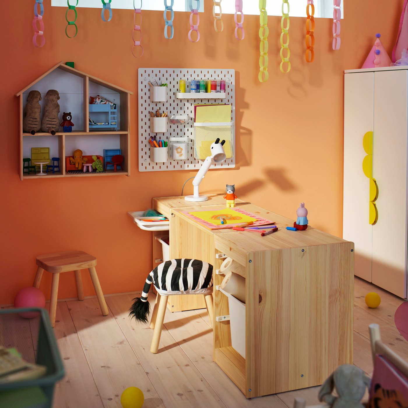 Two light white stained pine TROFAST frames with tabletop make a desk in an orange children’s room with a FLISAT stool.