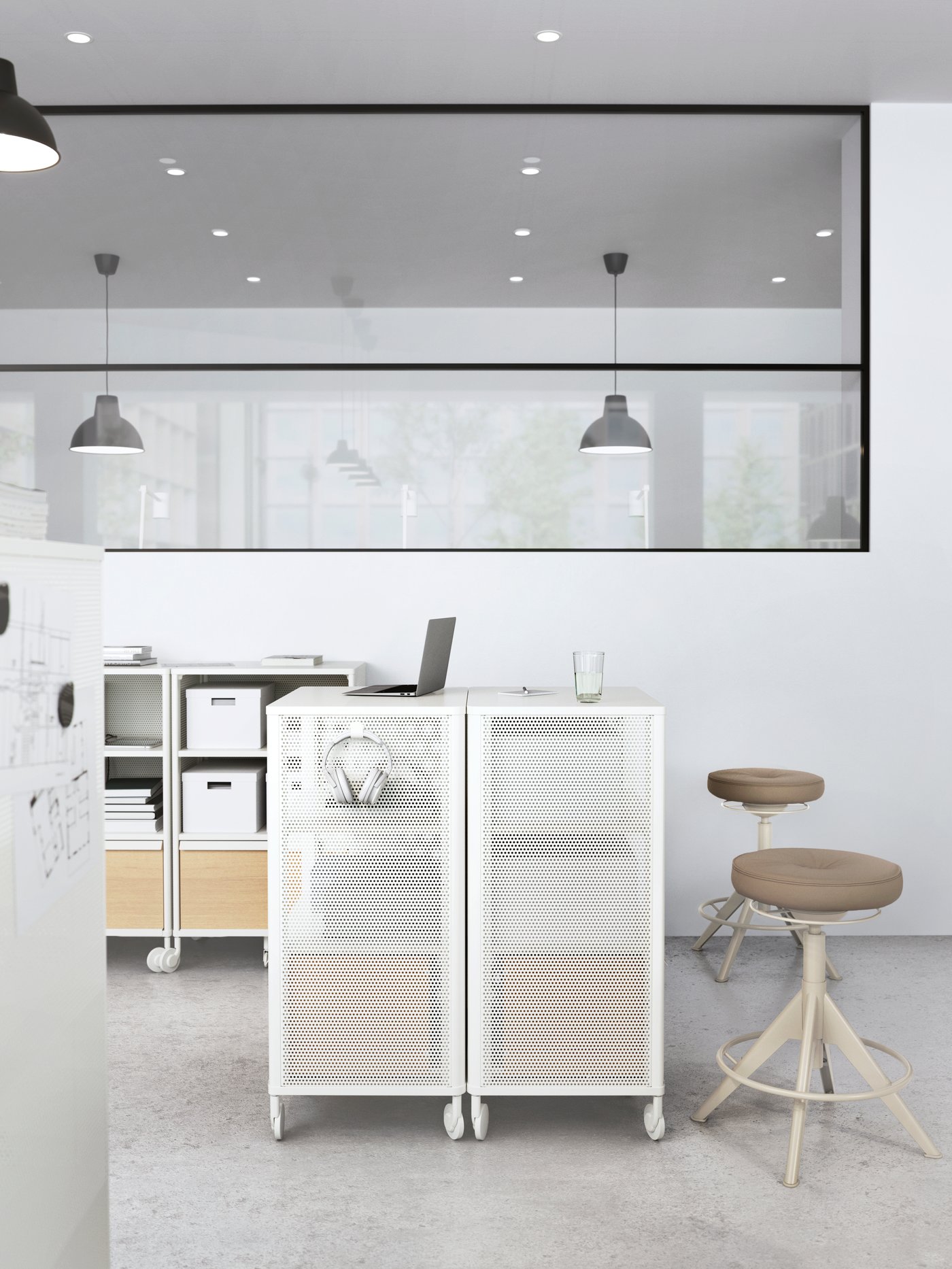 A laptop is sitting on one of two white BEKANT castors in the middle of an office room setting with two beige TROLLBERGET chairs behind.