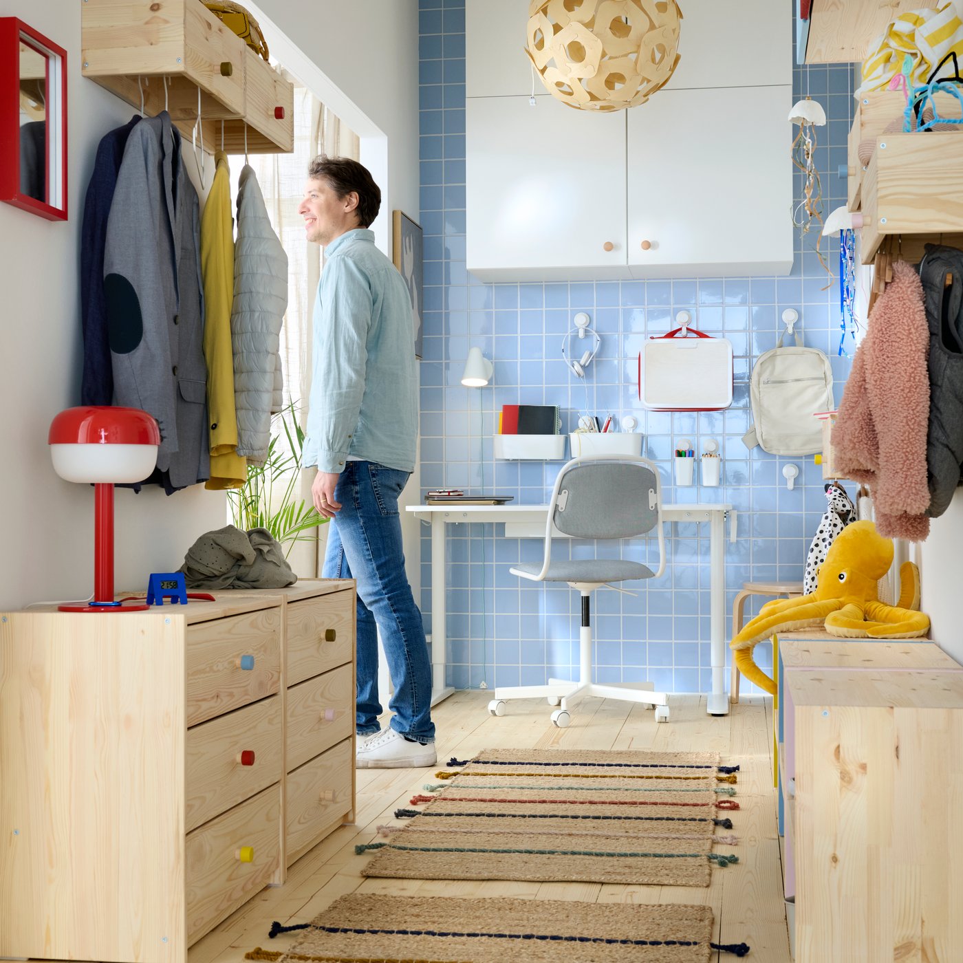 Een lange, smalle hal met opbergruimte voor alle hoogtes aan beide muren, met een lichtblauwe muur in de achtergrond met een bureau.