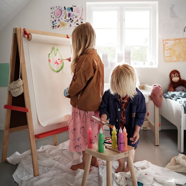 Zwei Kinder malen mit MÅLA Farben auf einer Zeichentafel. 