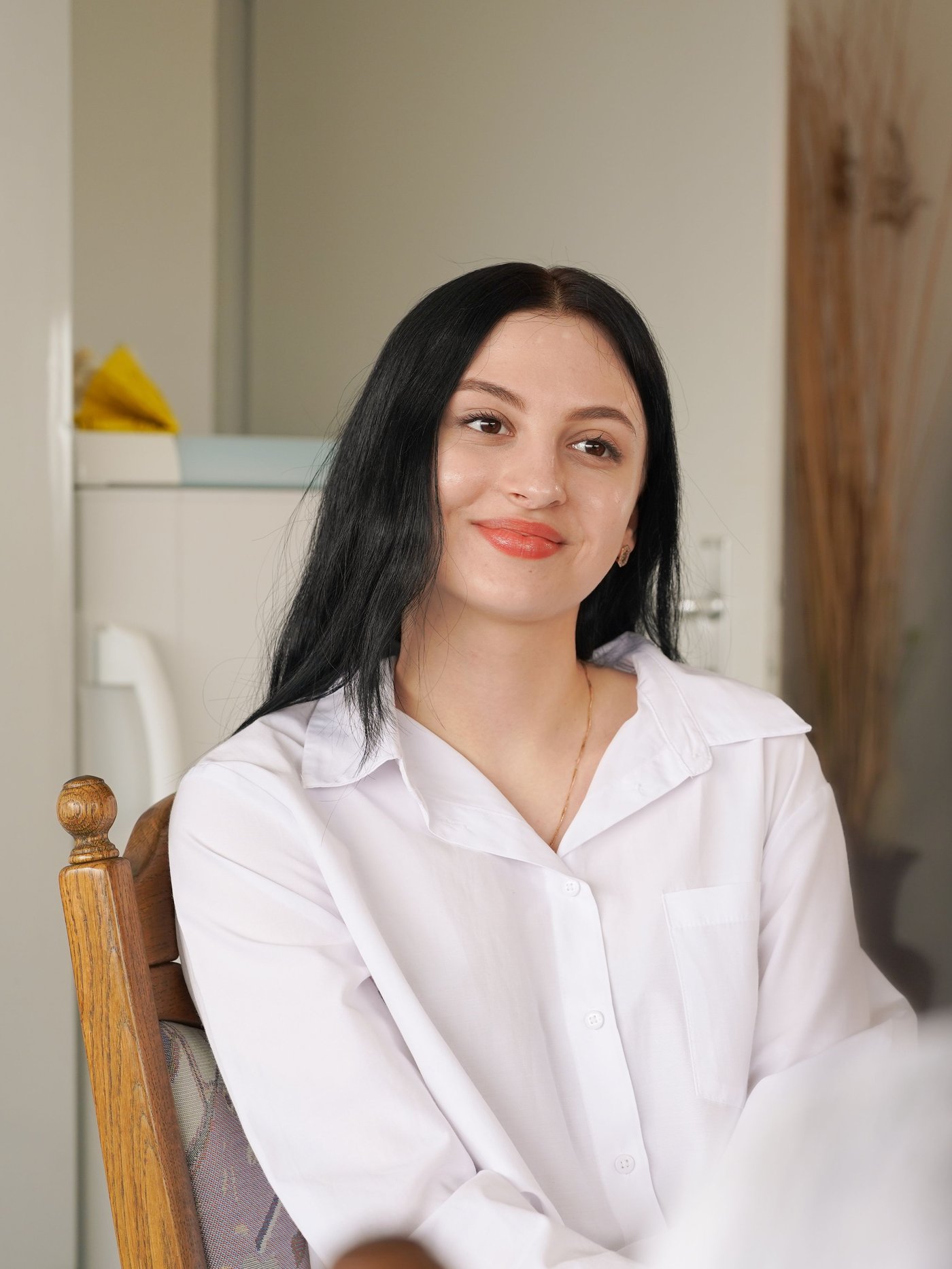 Portrait of a girl sitting in a chair wearing a white t-shirt.