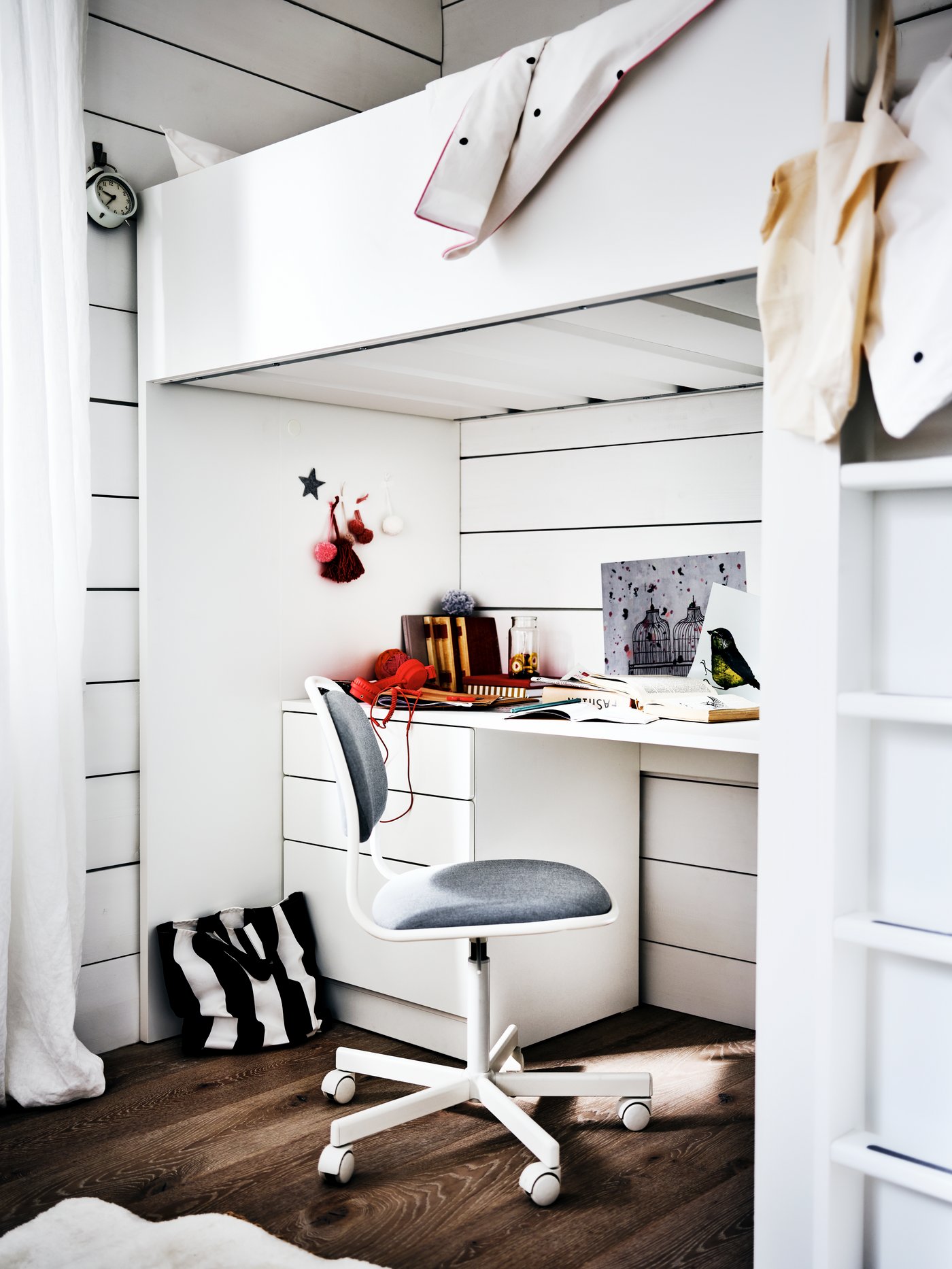 Pisalna miza in stol pod etažno posteljo z lestvijo.