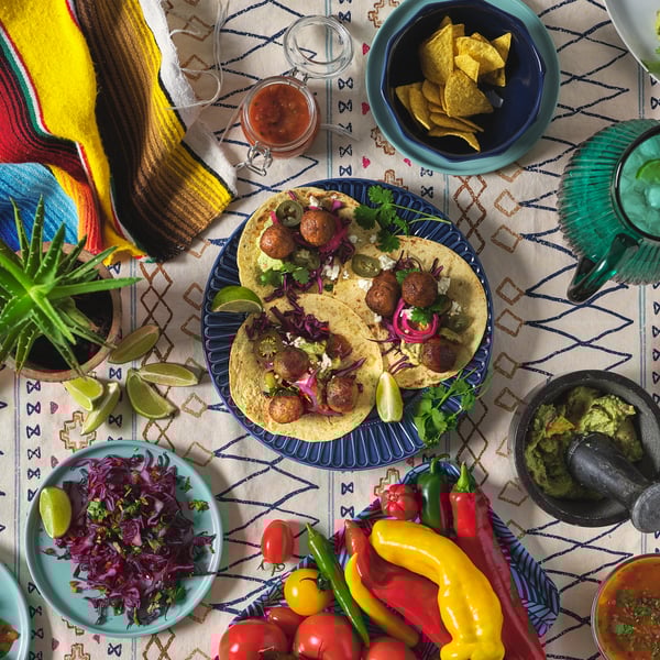 View from above of several colourful plates full of delicious food on a dining table.