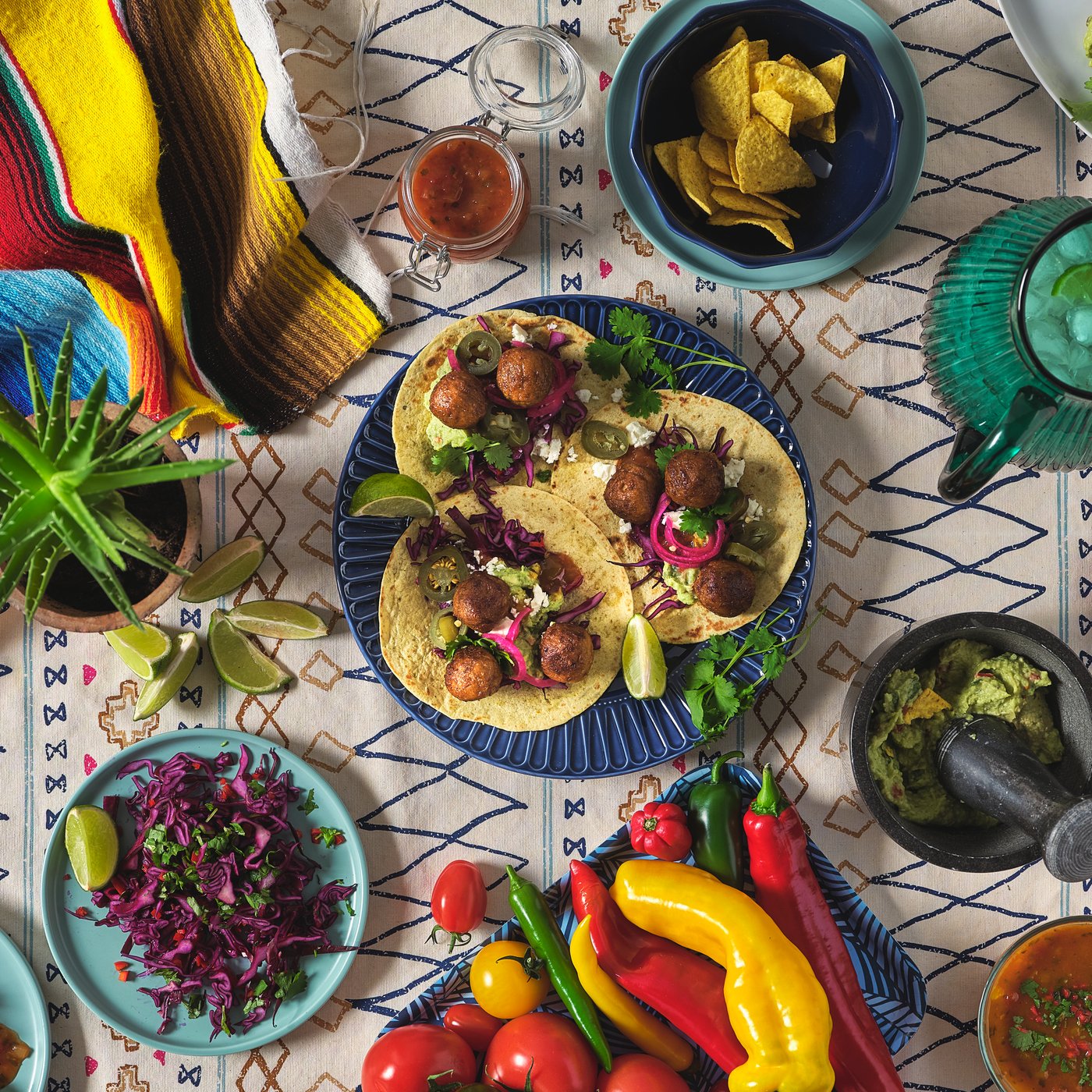 View from above of several colourful plates full of delicious food on a dining table.