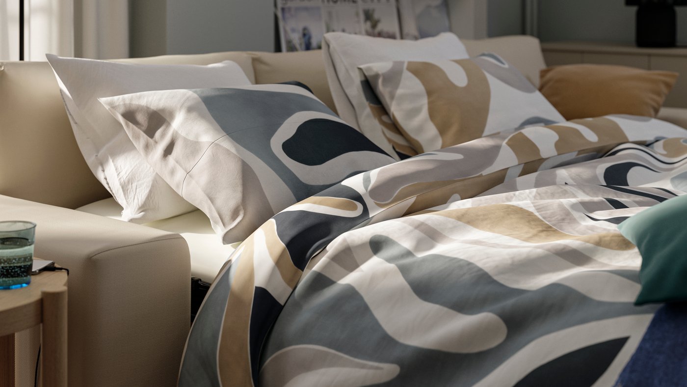 A VIMLE sofa-bed folded out as a handy and cosy double bed for overnight guests filled with MYGGLASVINGE bed textiles.
