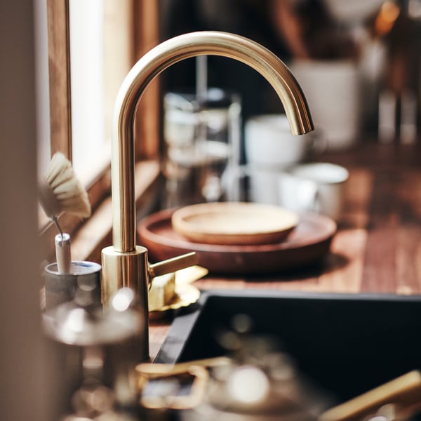 A DELSJÖN kitchen tap above a sink with dishes and cups in the background.