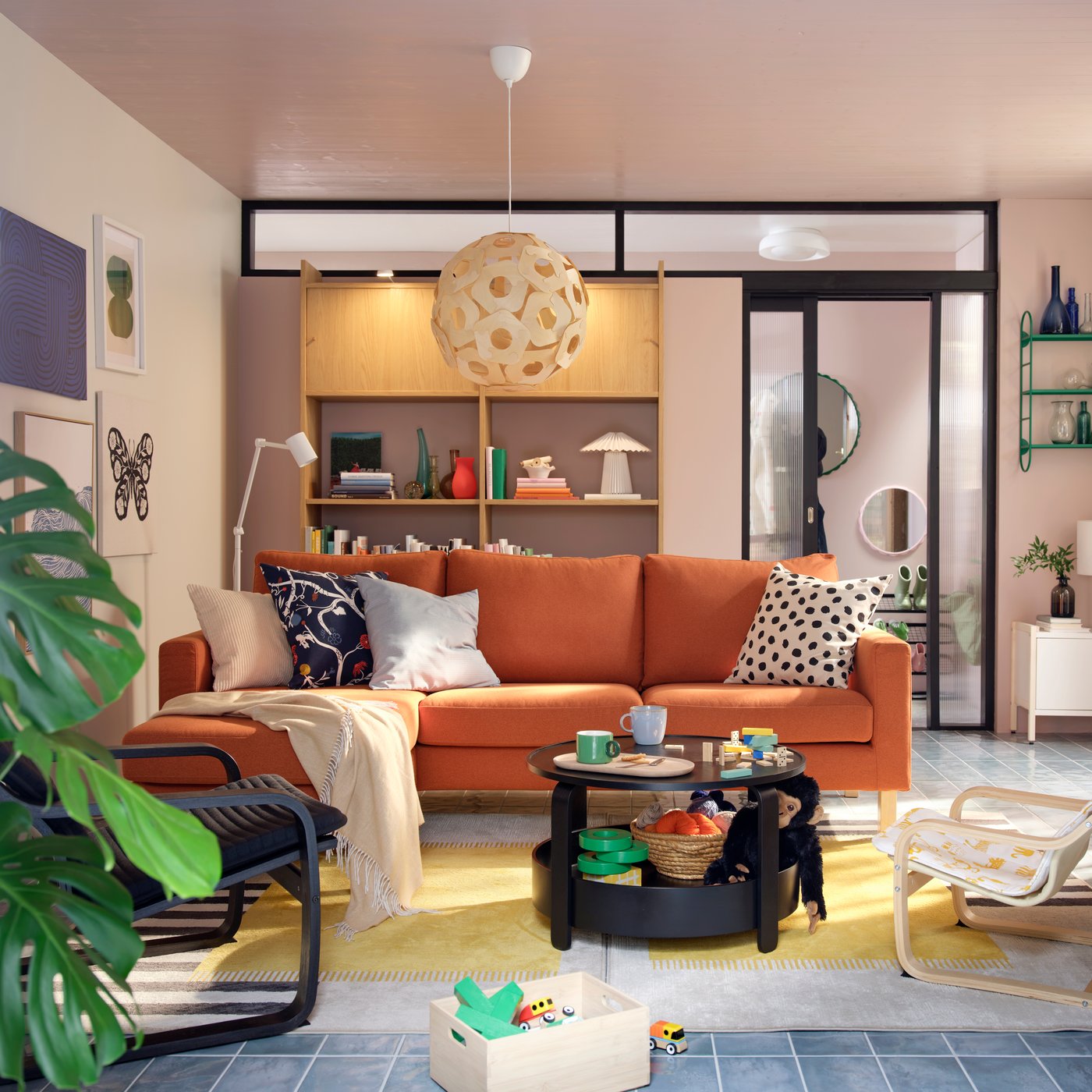A light living room with a red-brown SALTSJÖBADEN three-seat sofa flanked by armchairs, coffee table and toys.