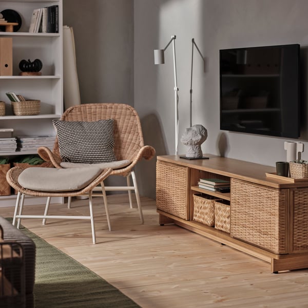 A plastic green KALLSINNIG glass in the living room with a rattan FRYKSÅS TV bench and armchair