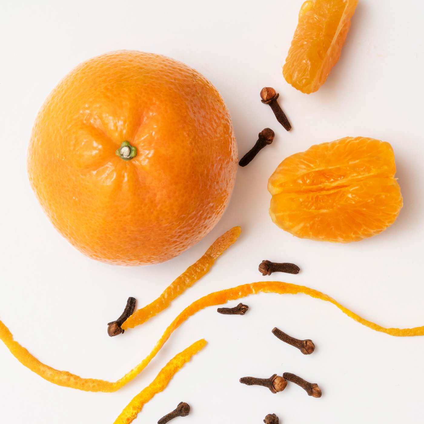 Vela aromática HÖKGÖK aroma Clementina y clavo en un recipiente de vidrio color naranja, en un espacio interior.