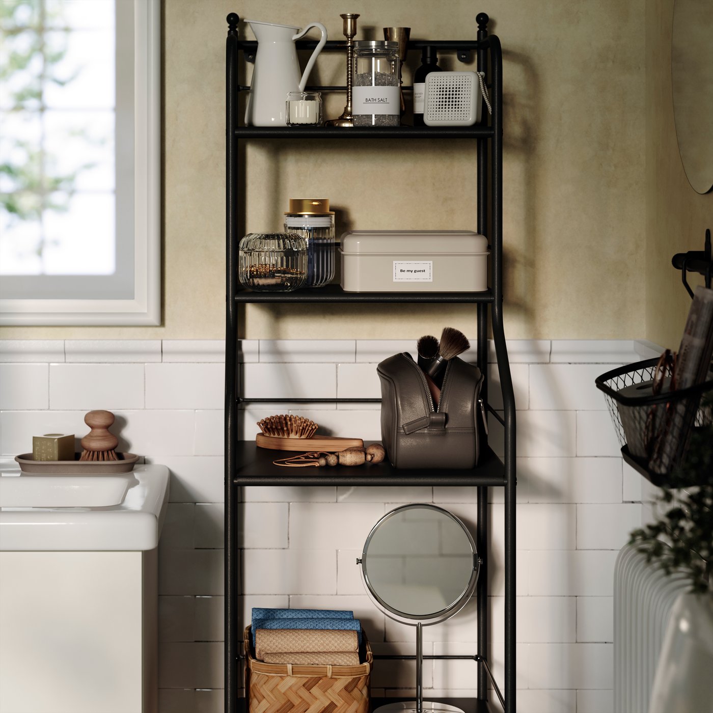 In un bagno in stile tradizionale, uno scaffale FRÖSJÖN in metallo nero su cui sono organizzati prodotti per la cura personale, oggetti decorativi e asciugamani.