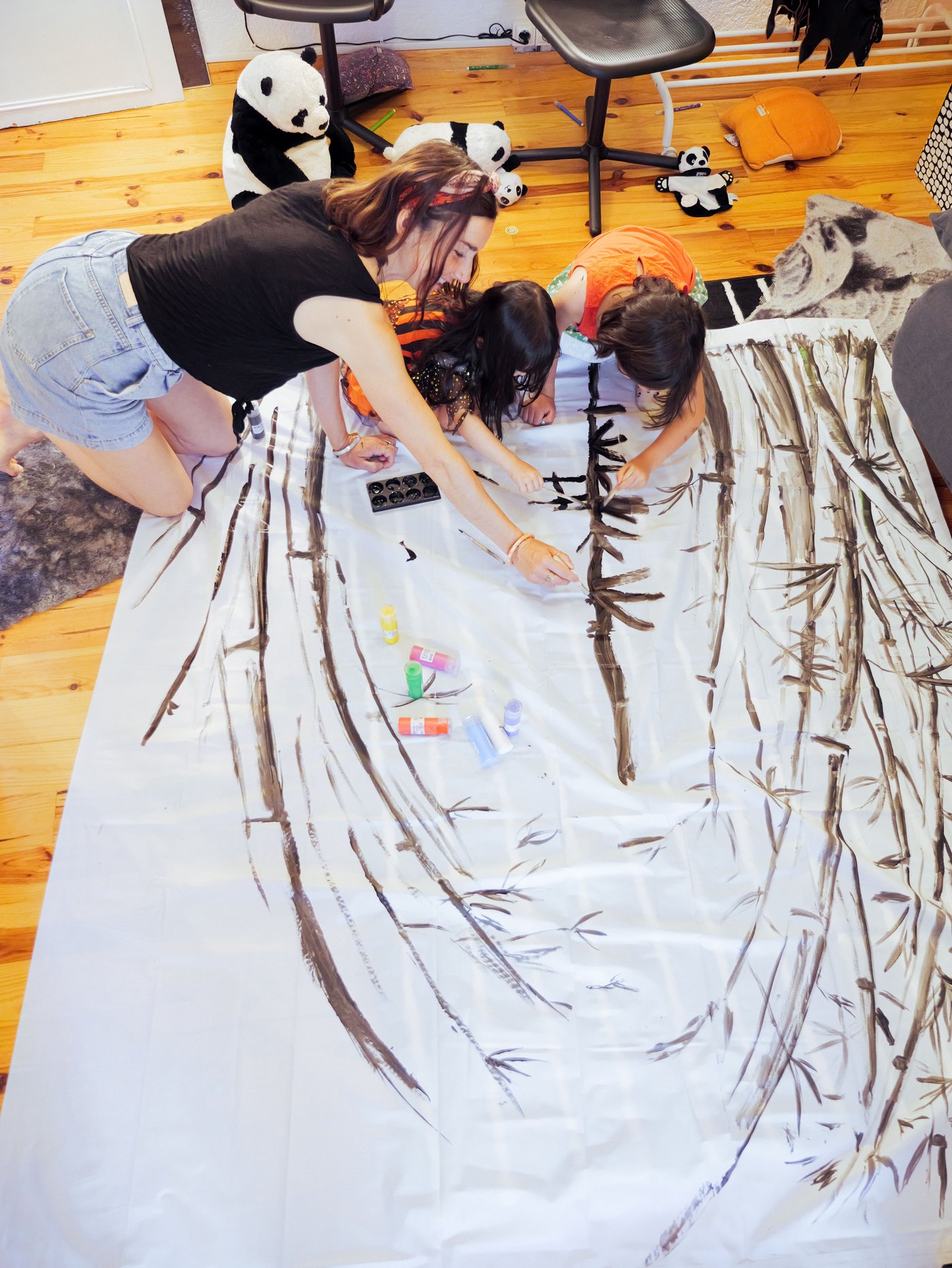 A mother and two children on the floor decoarte a BJÄRSEN shower curtain with MÅLA paint.
