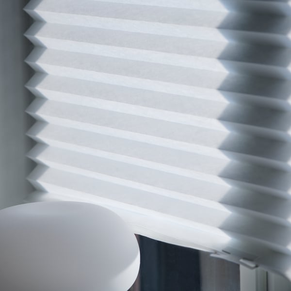A bedroom window with white SCHOTTIS block-out roller blind that covers the window.
