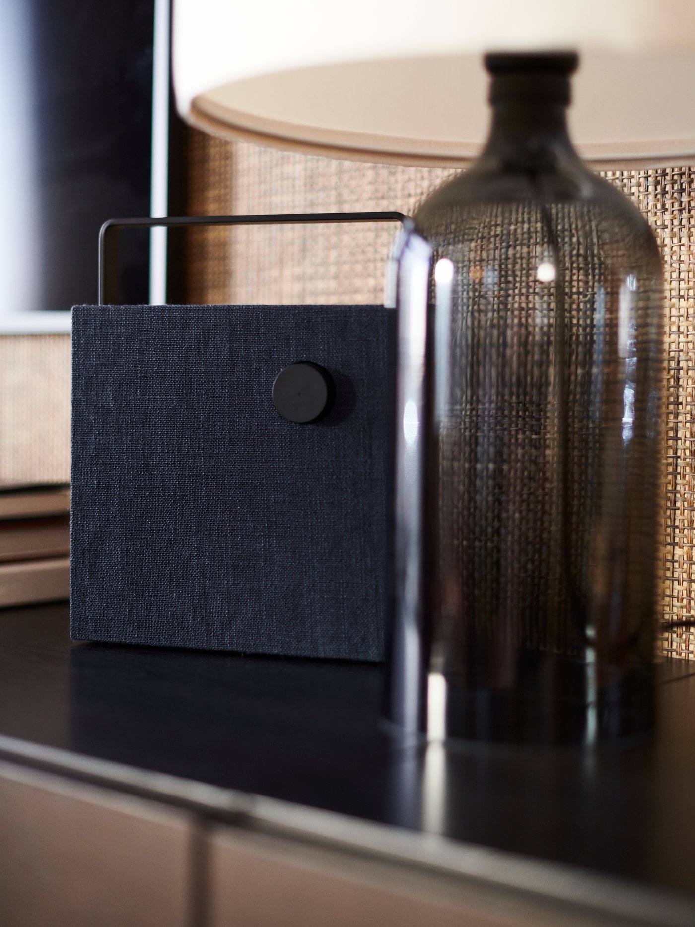 مصباح طاولة TONVIS على قاعدة زجاج داكنة اللون بجانب جهاز بلوتوث ENEBY.