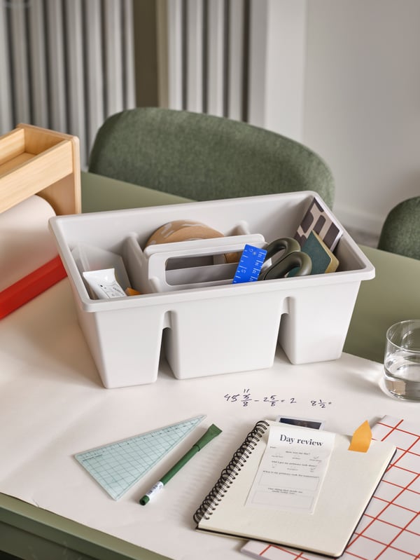 A light grey FÅNGGRÖDA insert with compartments stands on some paper on a green VIHALS extendable table.