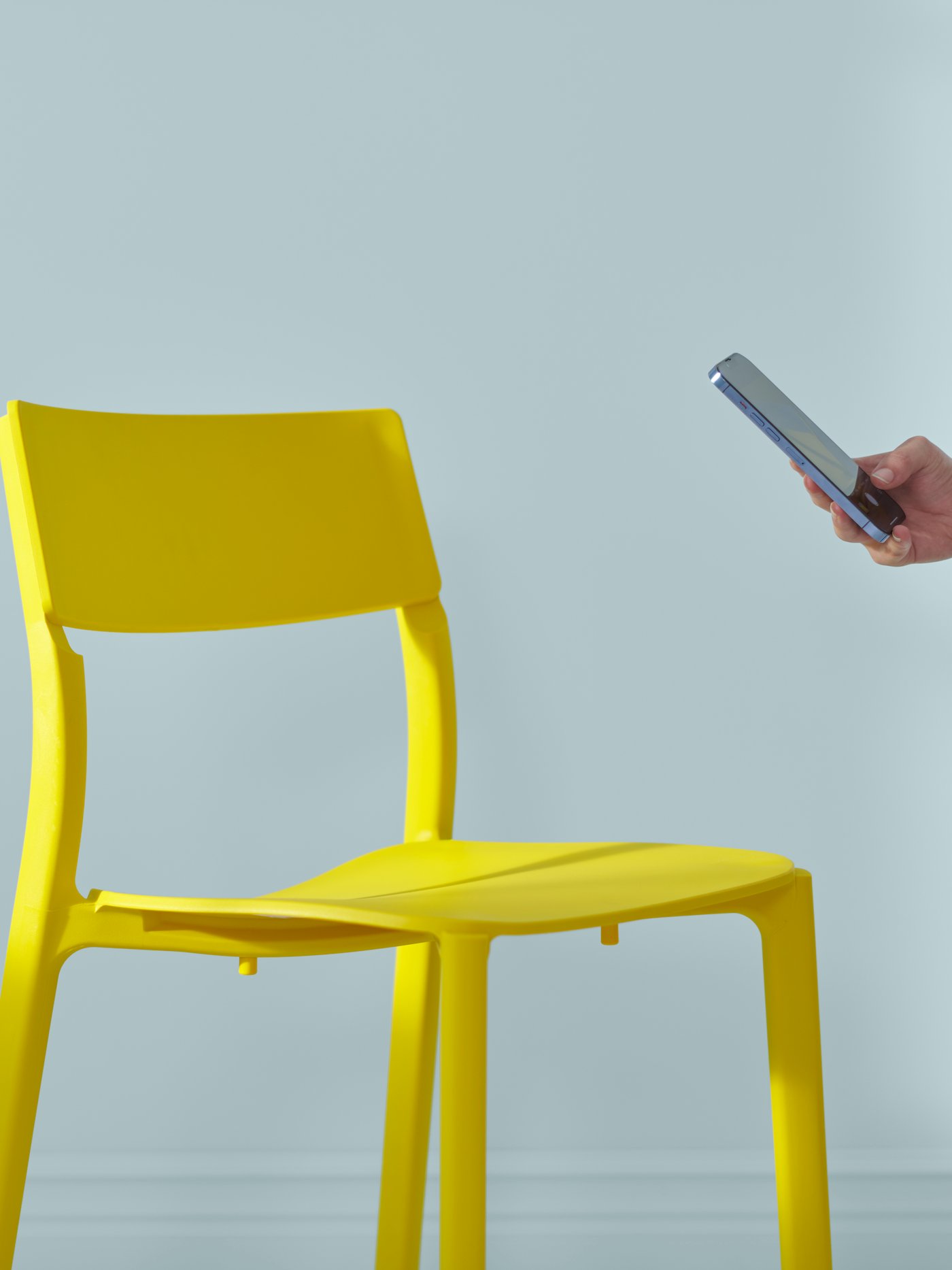Osoba s telefonom pregleda žutu stolicu.