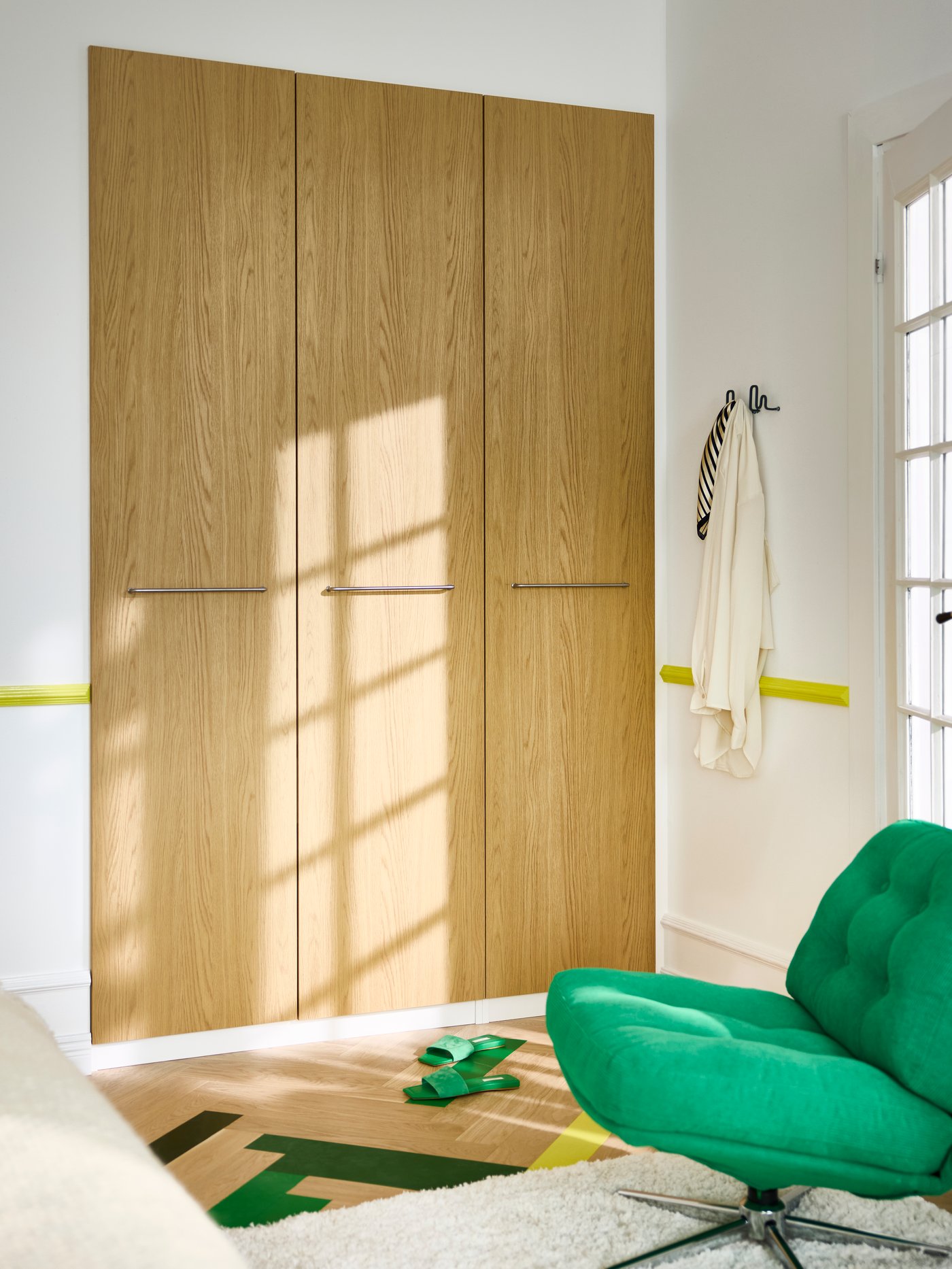 PAX/STORKLINTA garderobeskabe bagi, lysegrøn DYVLINGE drejelænestol, klare farver malet på parketgulv.