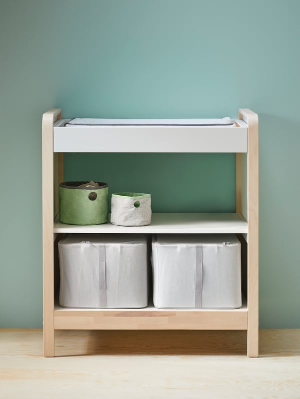 An ÄLSKVÄRD changing table in birch and white, there are two LACKISAR storage cases, and two LEN boxes on the shelves.