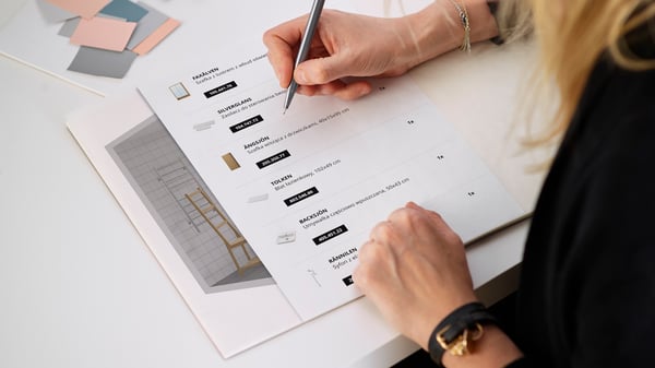 Osoba w długich włosach robiąca notatki na wydrukowanym na kartkach papieru projekcie łazienki.