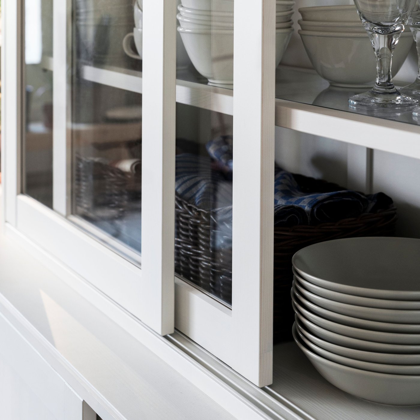 سلطانيات وأكواب وأواني مائدة أخرى على أرفف داخل خزانة بباب زجاج HAVSTA أبوابها مفتوحة.