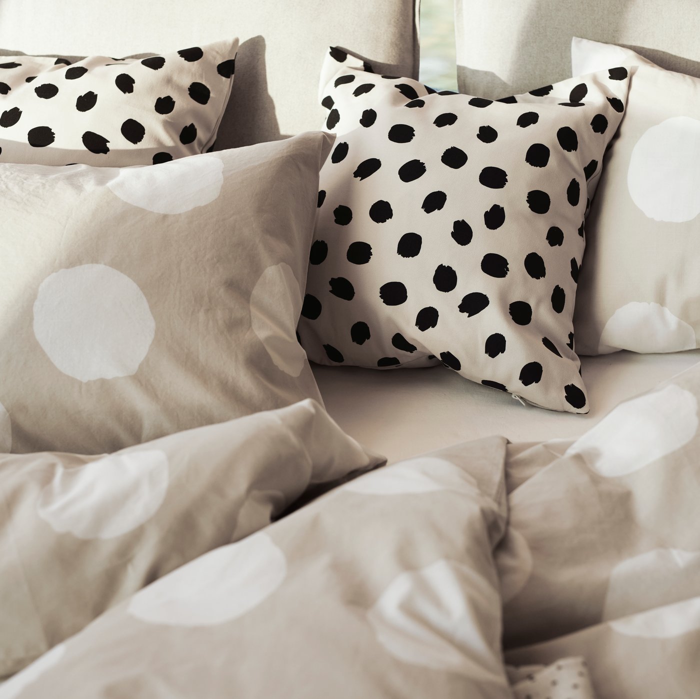 Prickiga prydnadskuddar och prickiga sängkläder i en säng.