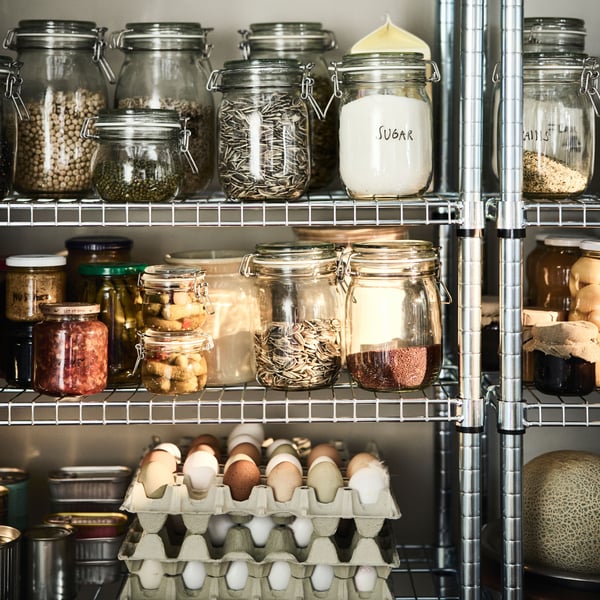 A close up of KORKEN jars full of foodstuffs and some eggs in cartons neatly arranged on an OMAR shelving unit.