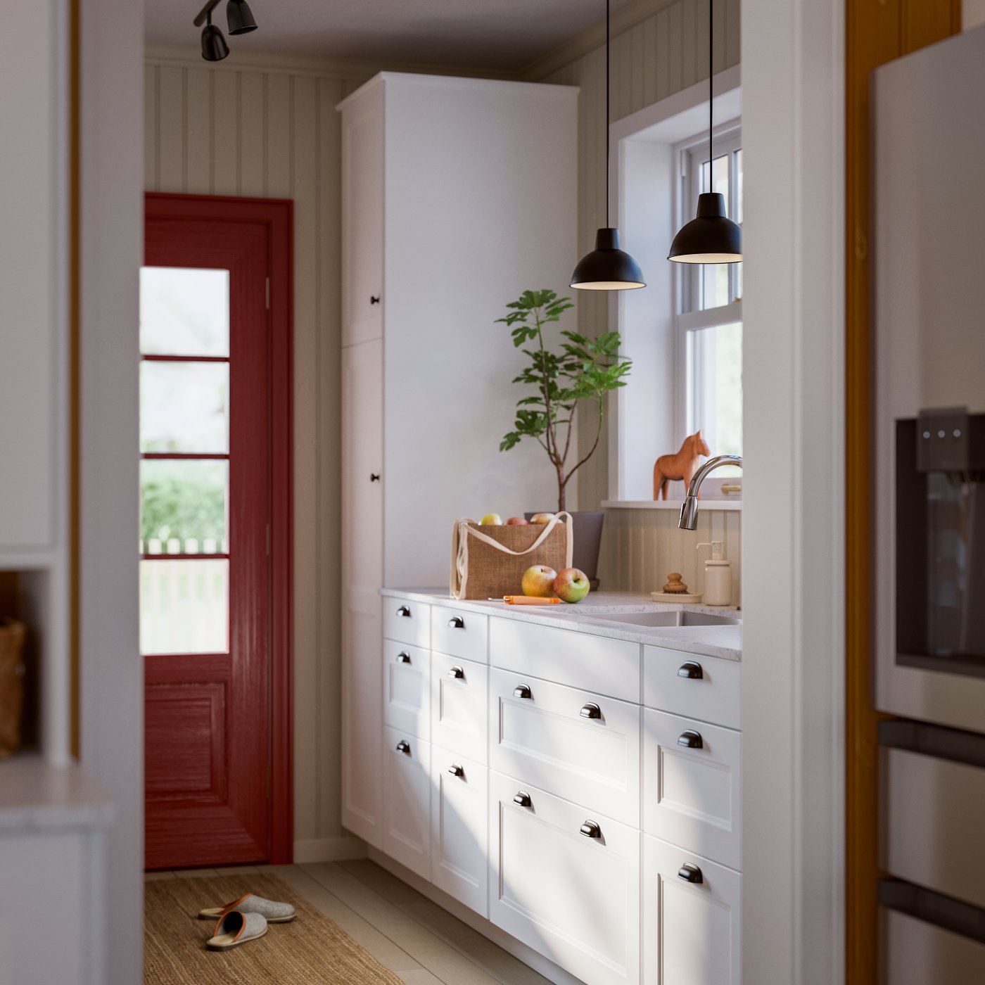 A bright mud room with white cabinets, a wooden door, and black pendant lights, featuring a green plant and fresh fruit.