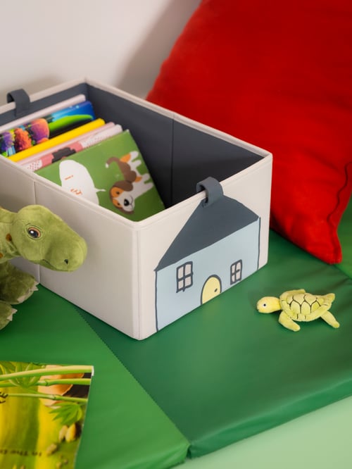 ベビールームと子ども部屋で、グリーンのPLUFSIG ペルフスィッグ折りたたみ式ジムマットの上にベージュのBARNDRÖM バーンドロームボックスが置いてある。横にはGURLI グルリクッションカバー。