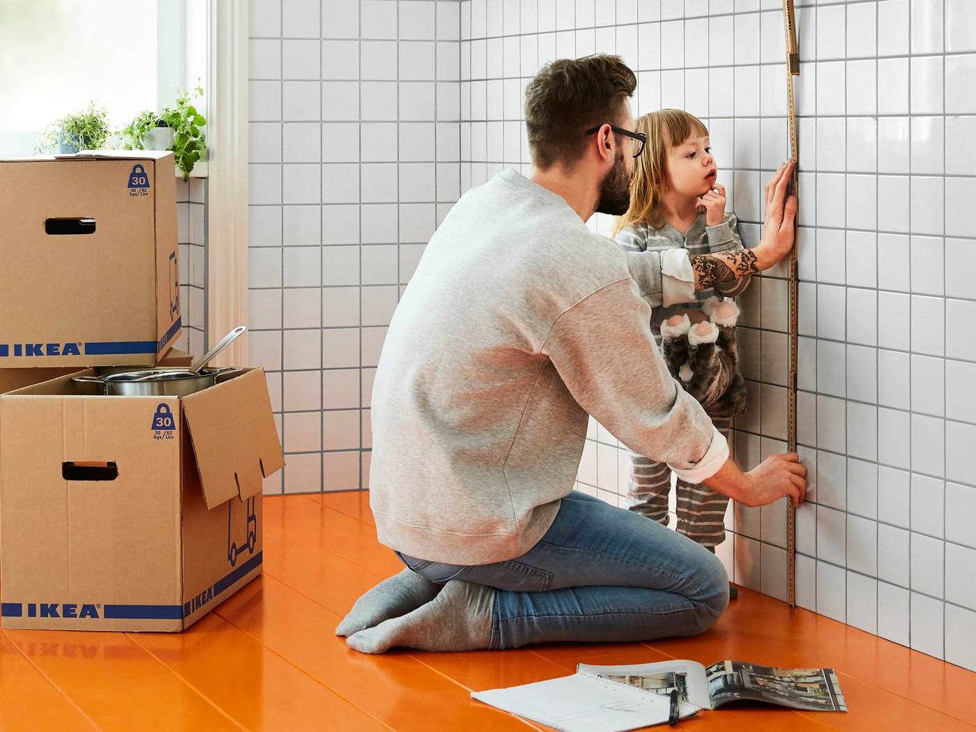 Man with his young daughter measuring a wall