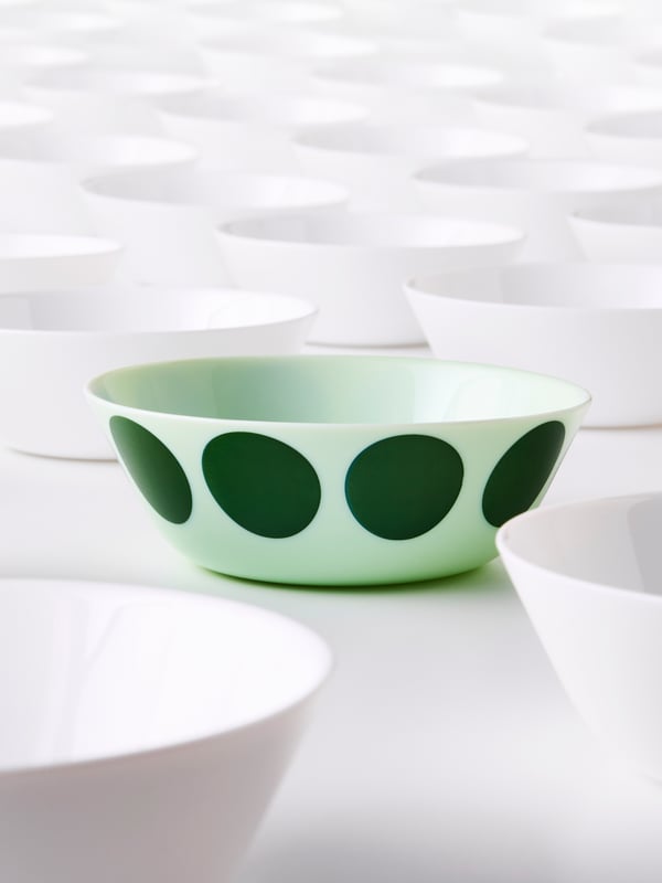 Light green OFTAST bowl with large green dots among a collection of white bowls.