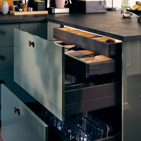Una cucina METOD con cassetti KNIVSHULT aperti e contenenti portatutto per cassetto UPPDATERA pieni di utensili per la cucina.