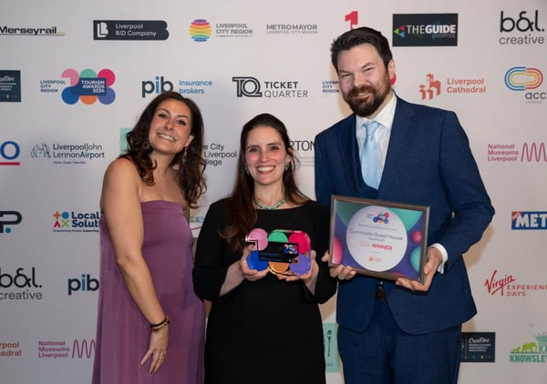 Sunnyside in front of a wall full of company logos showing the awards they've just received at an event.