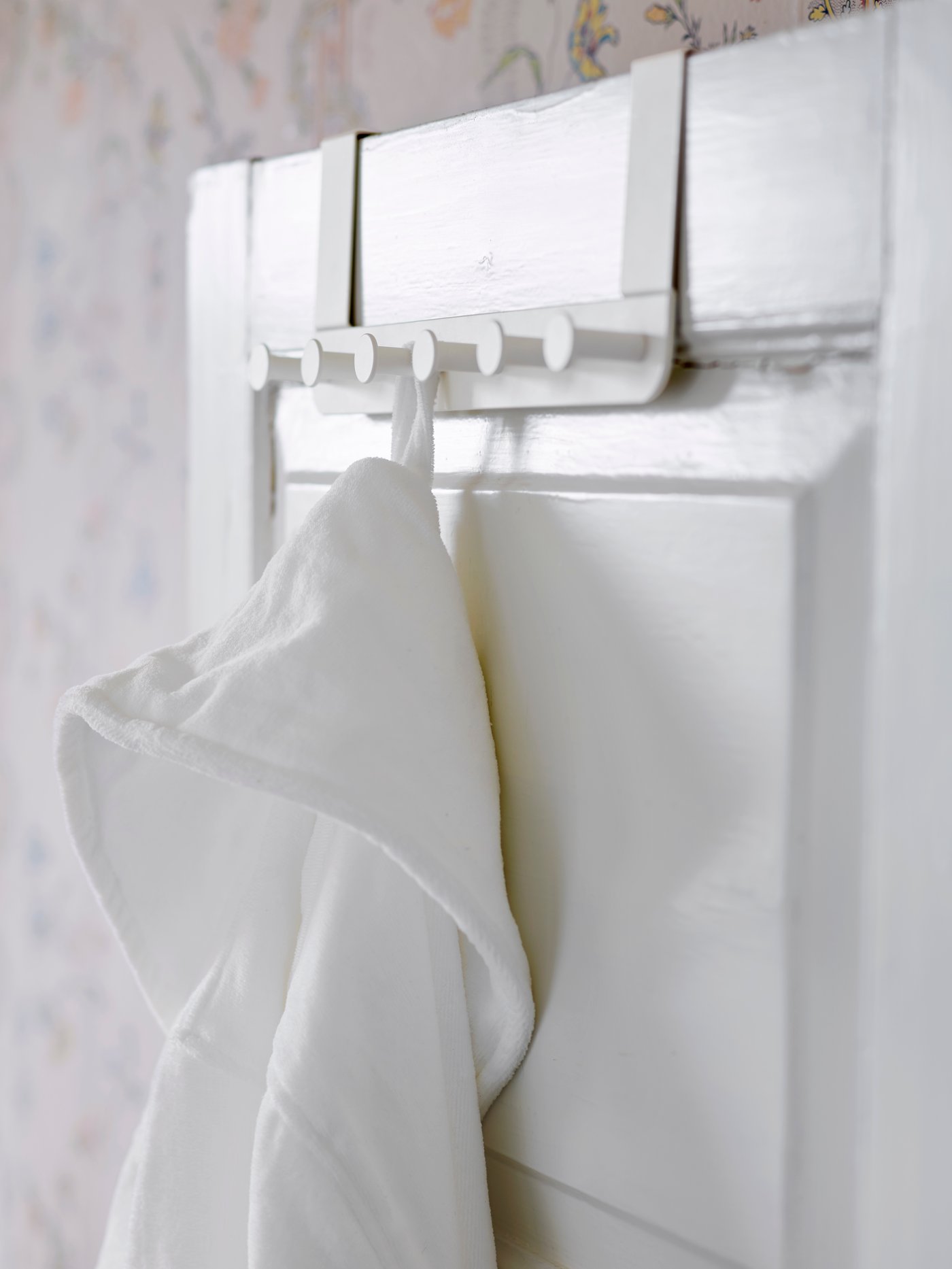 En hvid dør med en hvid badekåbe på en ENUDDEN bøjle til døre.