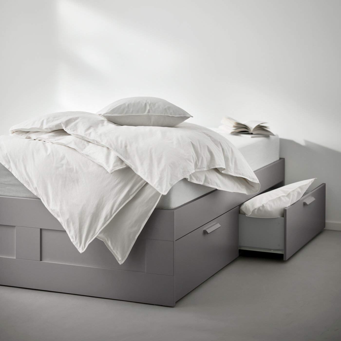 A grey BRIMNES bed frame with storage