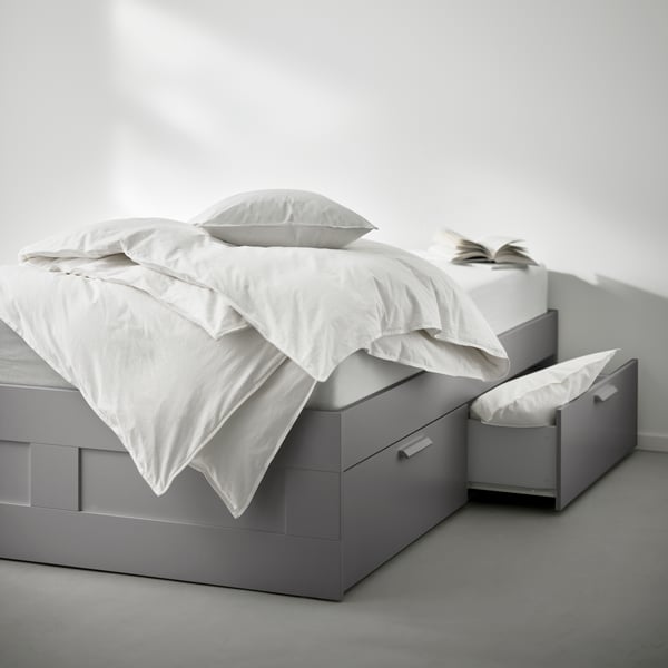 A grey BRIMNES bed frame with storage