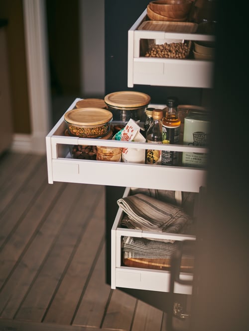 A MAXIMERA cabinet with containers and organisers holding jars, boxes and tin with various contents.