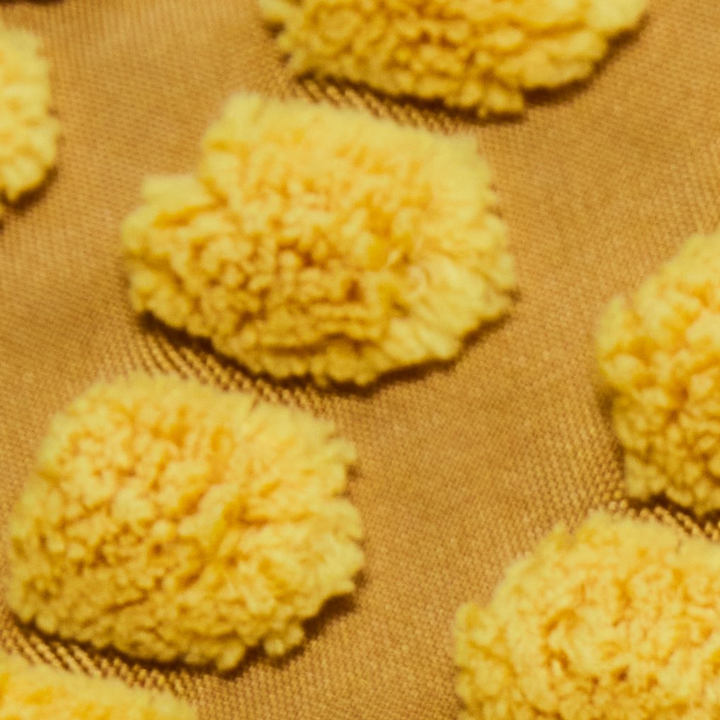 Dettaglio di una fodera per cuscino SVARTPOPPEL con dettagli in rilievo giallo.