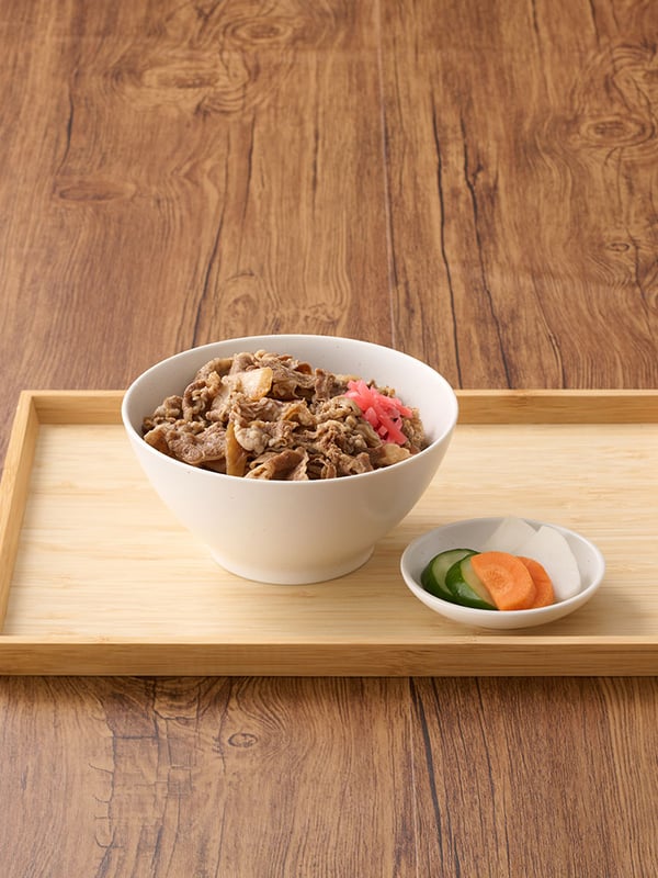 木製のトレーに載せられた牛丼（紅しょうが添え）と、きゅうり・にんじん・大根の漬物が入った小皿。

