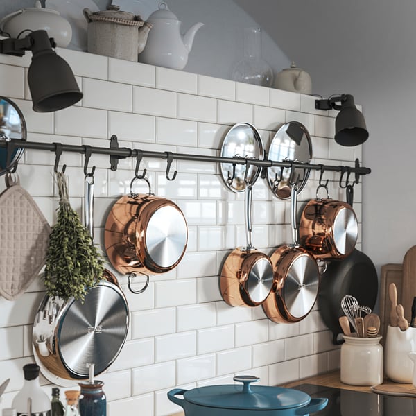 A HULTARP rail is mounted on a kitchen wall with several pots and pans hanging from the hooks attached to it.