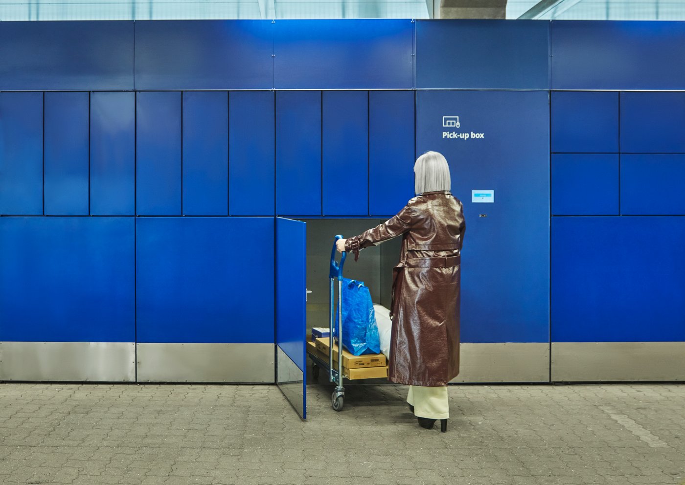 Person mit Einkaufswagen vor IKEA Pick-up-Boxen – Nutzung des kostenlosen Click & Collect Services für IKEA Family Mitglieder.