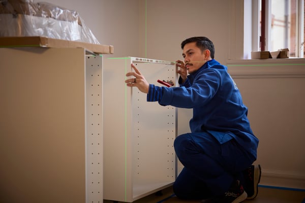 Ein IKEA Mitarbeiter montiert eine Küche. 
