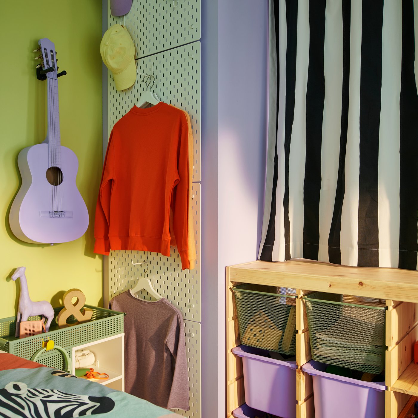 A TROFAST room divider with a black and white stripe curtain closed above it next to a column of four white SKÅDIS pegboards.