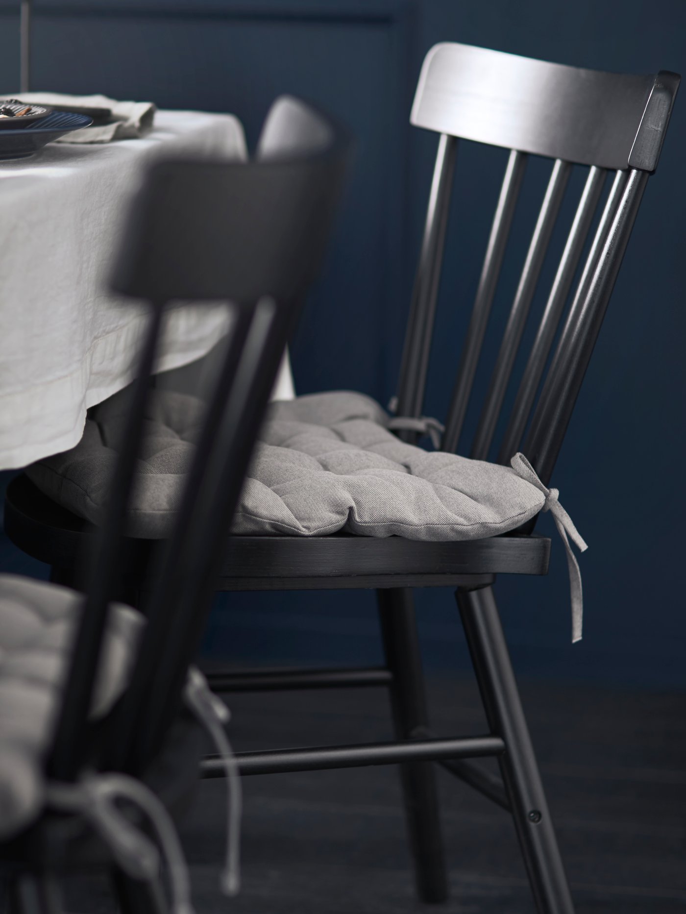 A black dining chair with a grey VIPPÄRT chair cushion in the dining room.