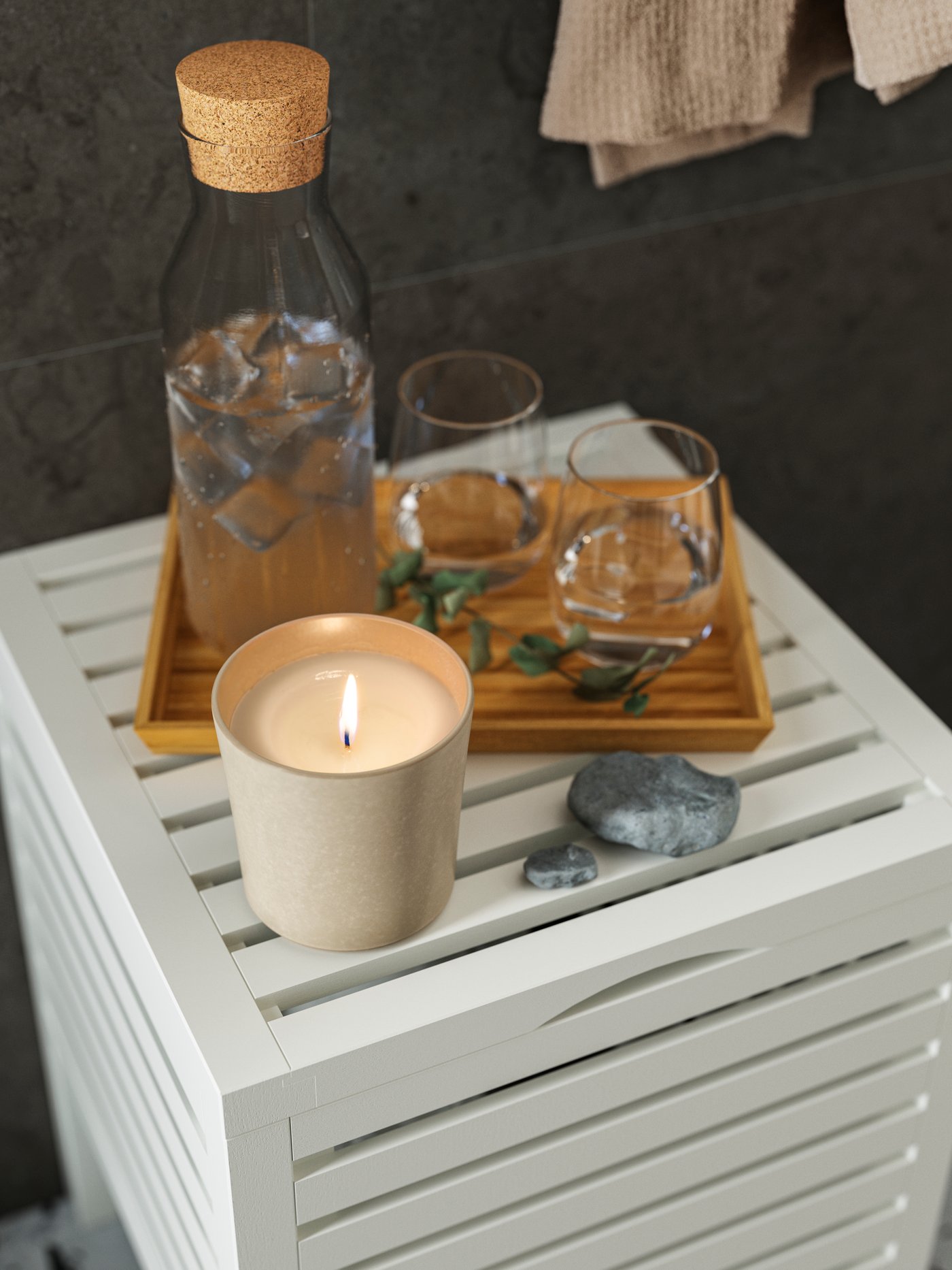 Duża świeca zapachowa JÄMLIK stojąca na białym stoliku w łazience.