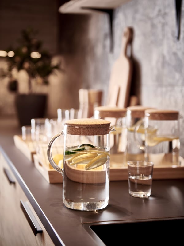 En detaljbild på en bringare med vatten och ett glas bredvid på en köksbänk.