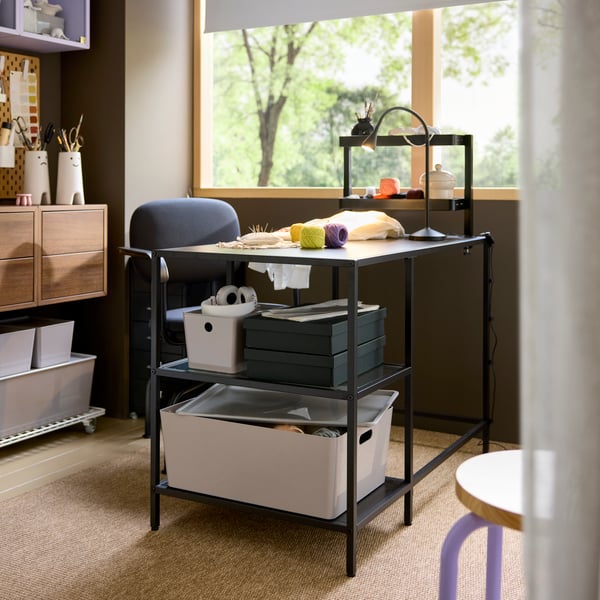 Escritorio VITTSJÖ negro lleno de cajas de diferentes tamaños.