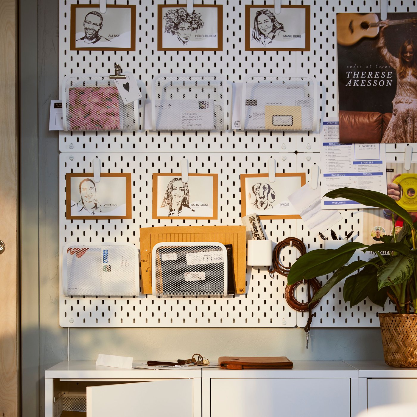 A light office interior a row of white HÄLLAN cabinets with sliding doors beneath a combination of white SKÅDIS pegboards.