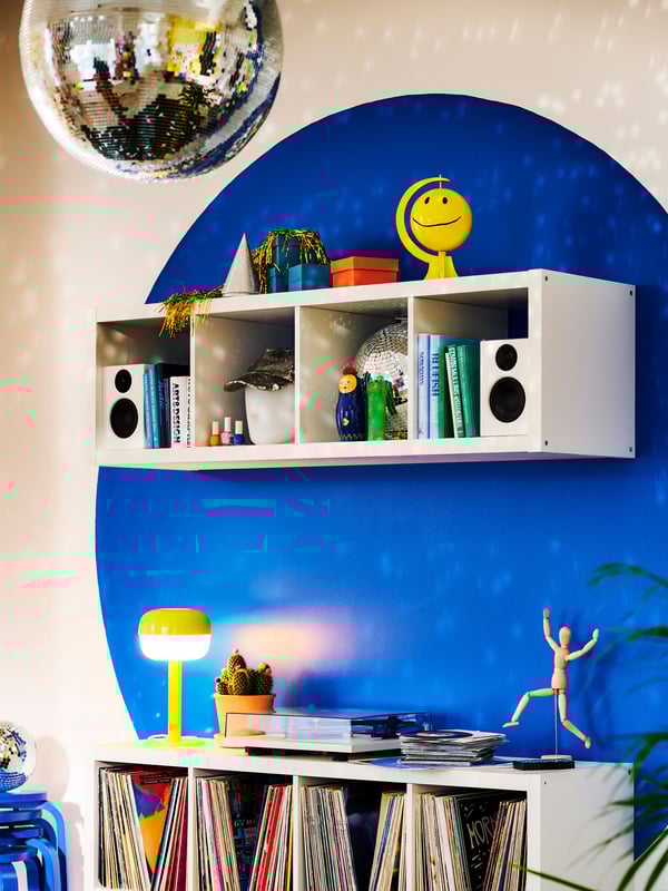 A blue painted wall with white EKET cabinets and a yellow BLÅSVERK lamp.