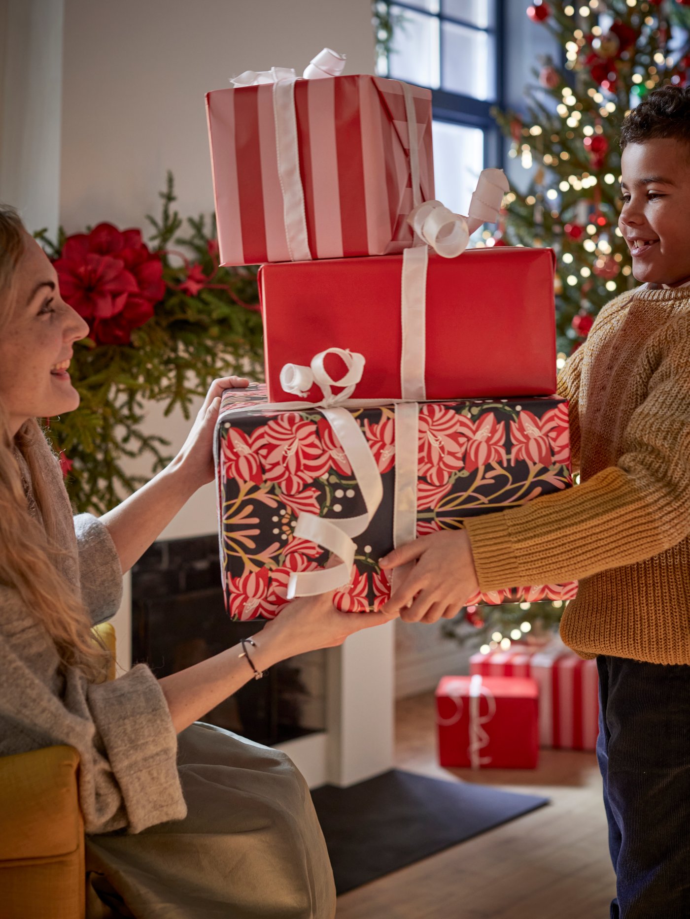A kid receiving presents wrapped in VINTERFINT wrapping paper from a woman.