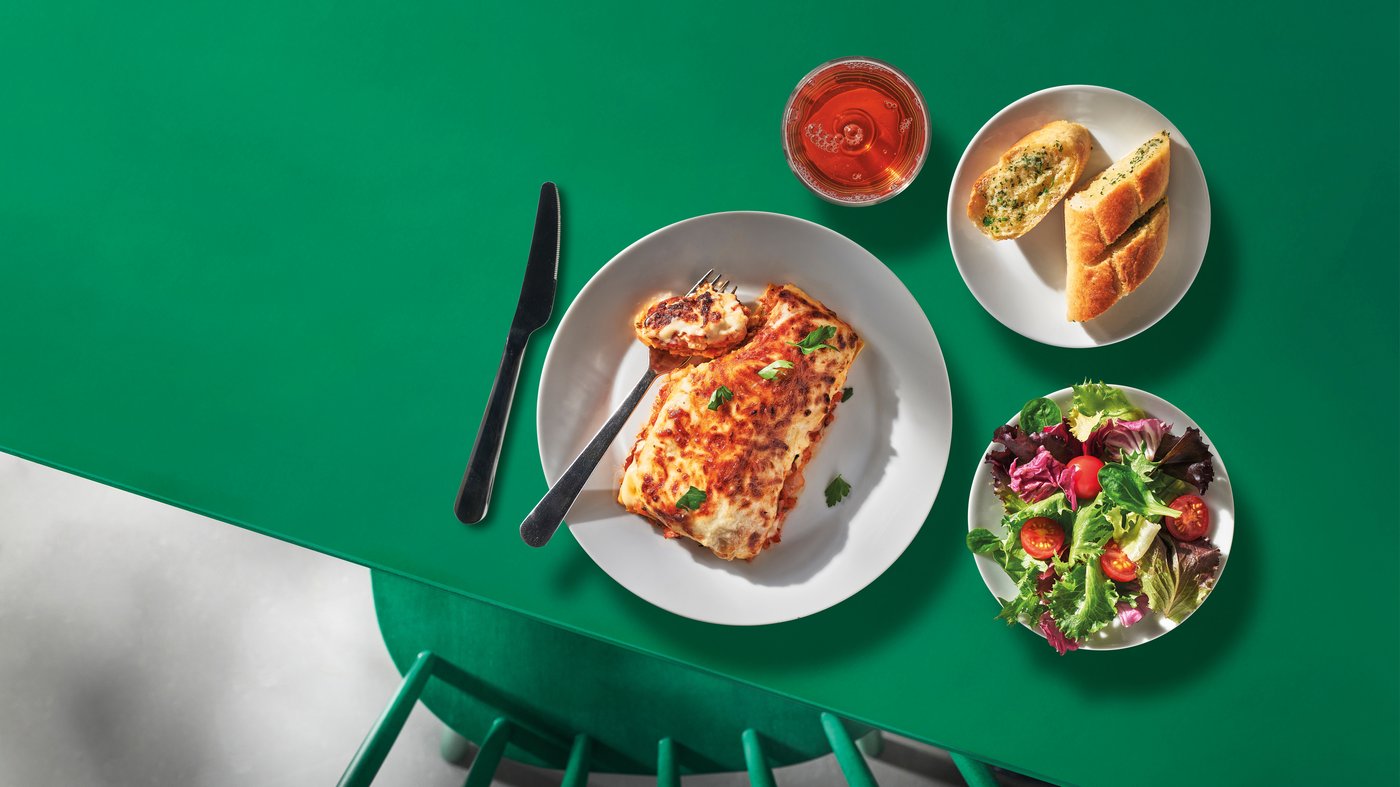 Lasagna, garlic bread, salad and dispenser drink.